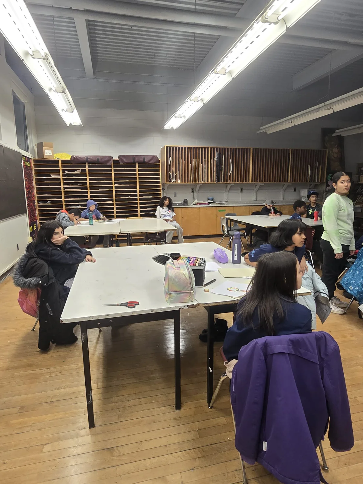 Youth participants seated at workshop studio tables engaged in learning