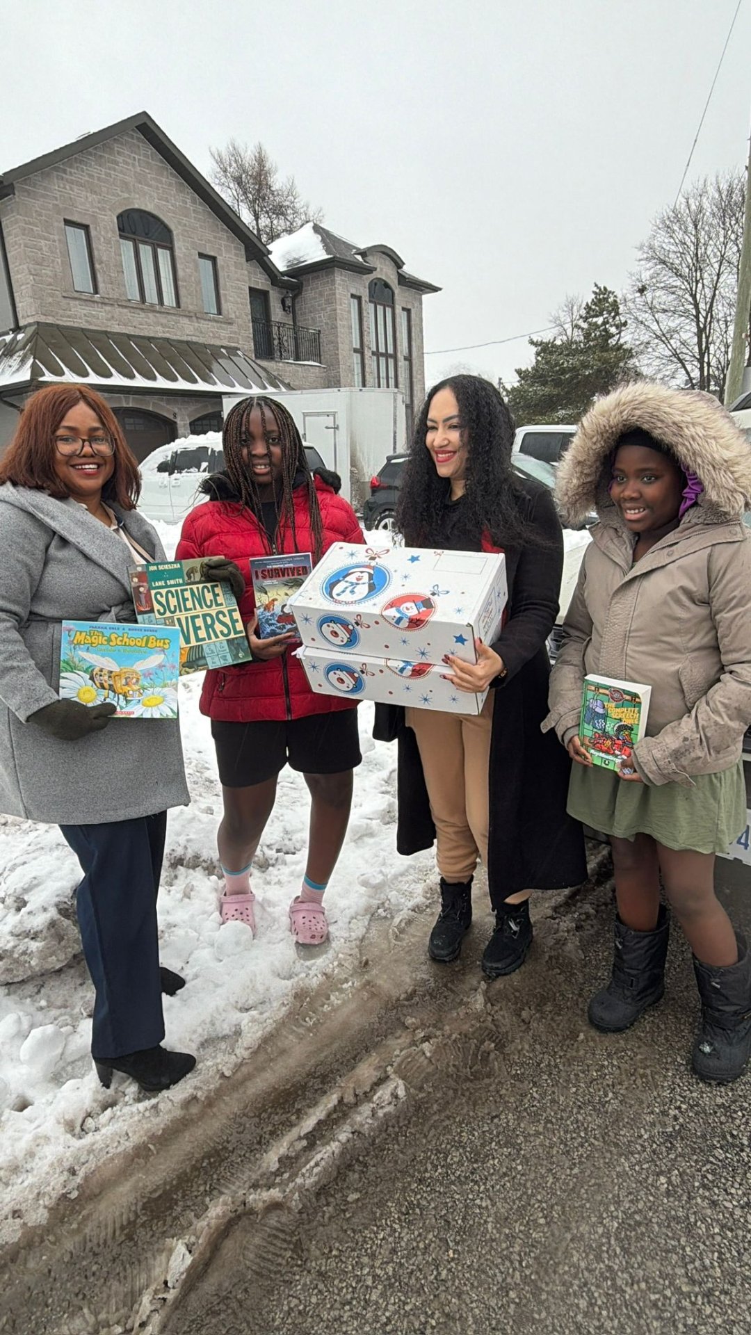 Children holding inspiring books and holiday gift hampers in the snow