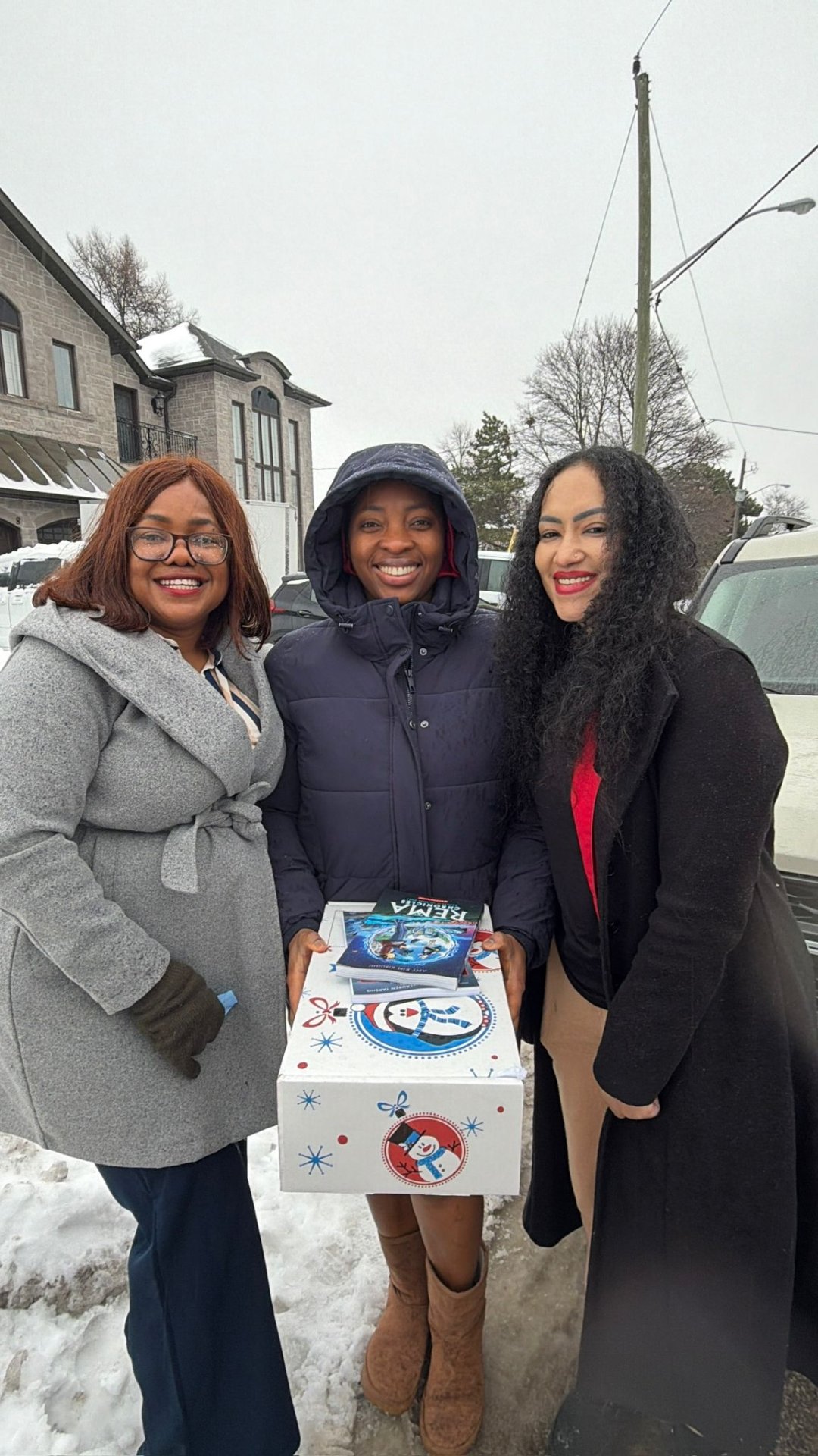 Smiling women leaders holding book packages and gift boxes in snowy North York