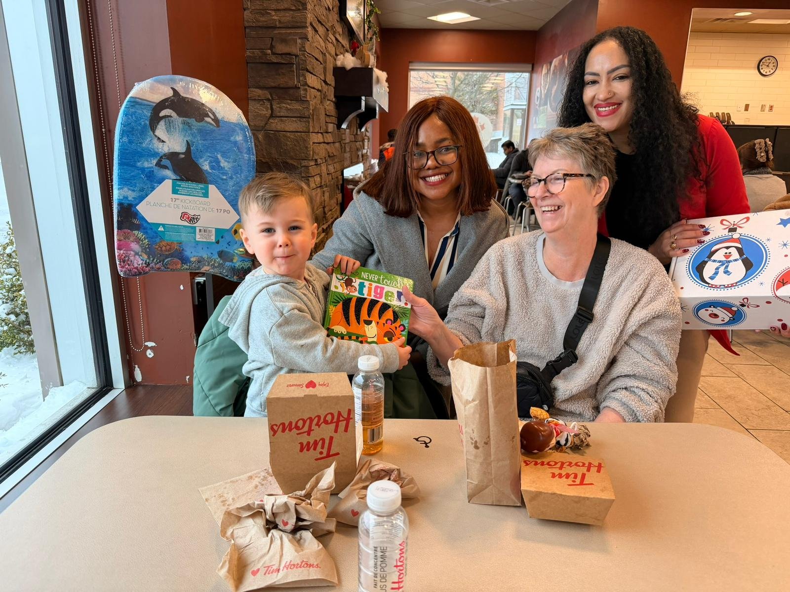 Smiling young toddler holding a storybook with family and community supporters